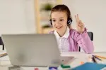 Kulaklıkla online İngilizce dersi alan mutlu çocuk